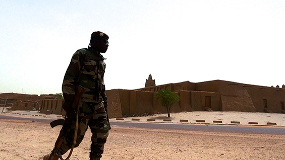 A soldier patrols in front of Djinguereber Mosque, Timbuktu. Image by Francois Rihouay from ‘The Destruction of Memory’. © Vast Productions USA 2016