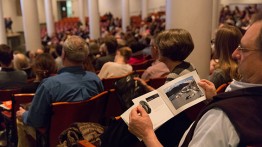 An audience member views the program that includes many striking photos