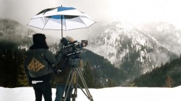 Photo by Matt Anderson. Michael Gerner holds an umbrella over cinematographer David Black to get a shot of the mountains in Mont