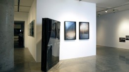 Installation view of Oscar Tuazon’s Black Slab, 2008 (center right) and Afognak (triptych), 2008 (center left)