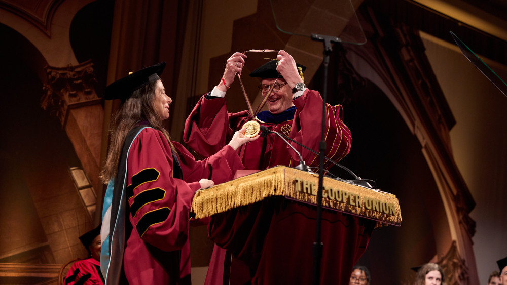 Man receives medal from woman both in regalia