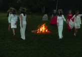 Women honor the fire by dancing with crowns of field flowers on their heads