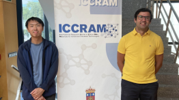 Two people standing to the side of a full length poster.