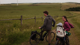 Image of more grasslands with two people stopped on bikes.