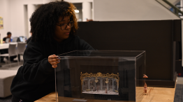 Zekaiya Whittington installing a model of the Todd Haimes Theater by Marsha Ginsberg A’83