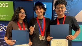 Three students hold winning certificates and wear medals