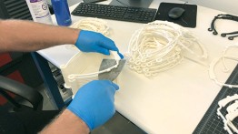 Volunteers cut 3D-printed components for protective face shields.