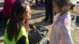 Helena Zhu greets a young refugee who, moments before, had been pulled off a plastic boat