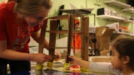 Madeline Foster's helping a young child build a structure out of cardboard