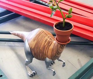Dinorsaur with a terrocota pot and a small plant