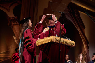 Man receives medal from woman both in regalia