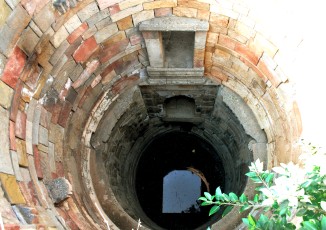 Arched openings in its stepped corridor provide access to a large, open well shaft with groundwater in Jethabhai vaav, Ahmedabad.