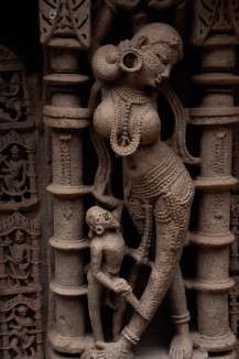 A sculpture depicting a maiden with a dwarf admiring her beauty at the Queen's Stepwell. 