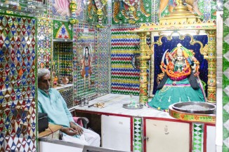 A priest sits next to an idol of a goddess in Ambe maata vaav near Malav talav in Ahmedabad. The stepwell has been converted into a temple with a central shrine covered in mirrorwork. 