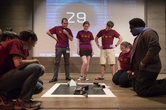 Engineering students watch over their sumo robots in heated battle