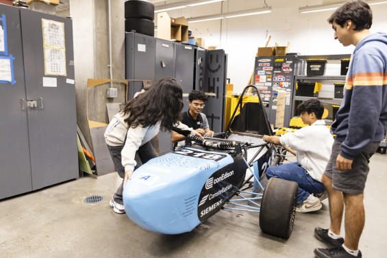Students work on their sponsored Formula race car in the shop.