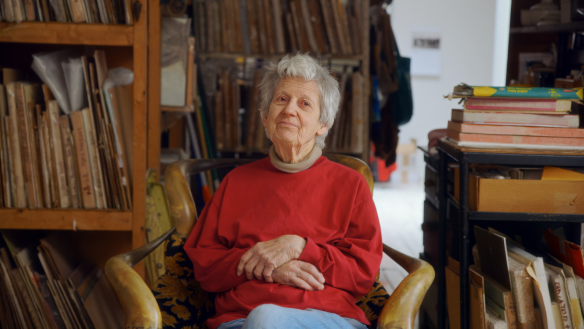 Lois Dodd in a red sweater seated 
