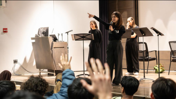 photo of three people on stage in school auditorium